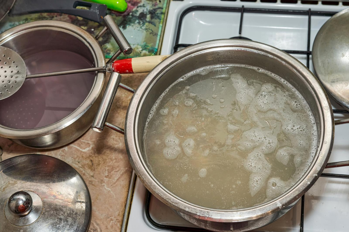 Saucepan with soup simmering on a stove top.