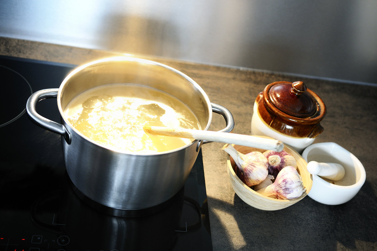 Soup boiling in a pot with various ingredients around it.