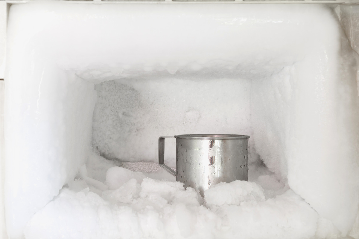 Freezer compartment full of ice and a metal mug.