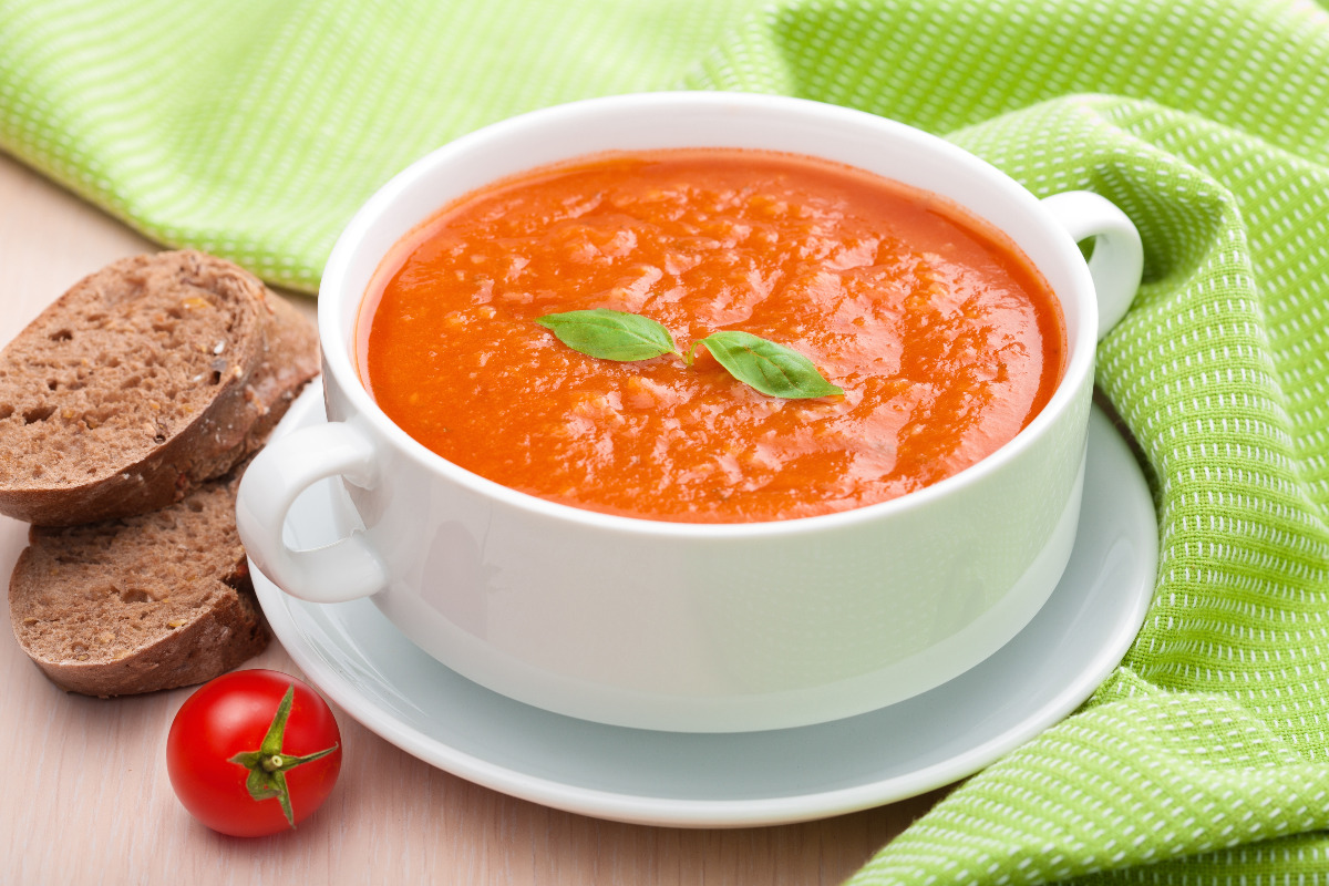 A bowl of classic tomato soup with a side of bread.