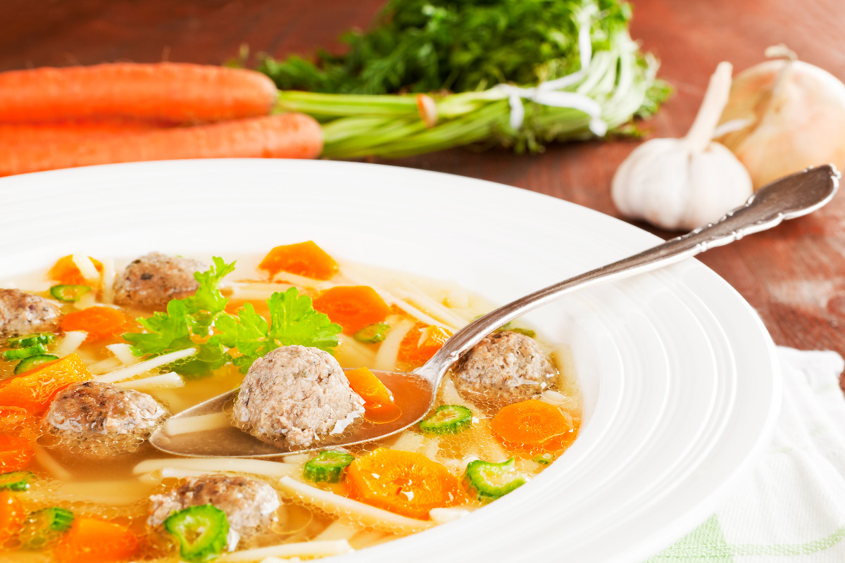 A bowl of nutrient rich soup with meatballs.