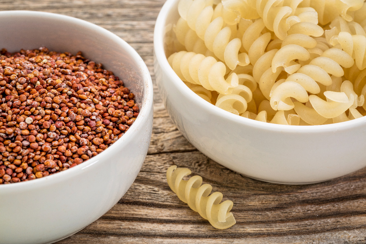 Separate bowls of quinoa grain and pasta.