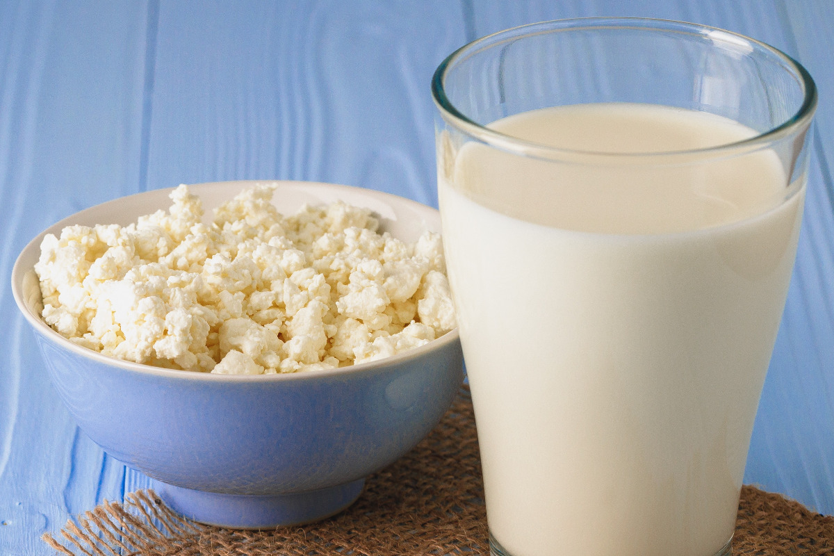 A bowl of cream cheese and a glass of milk.