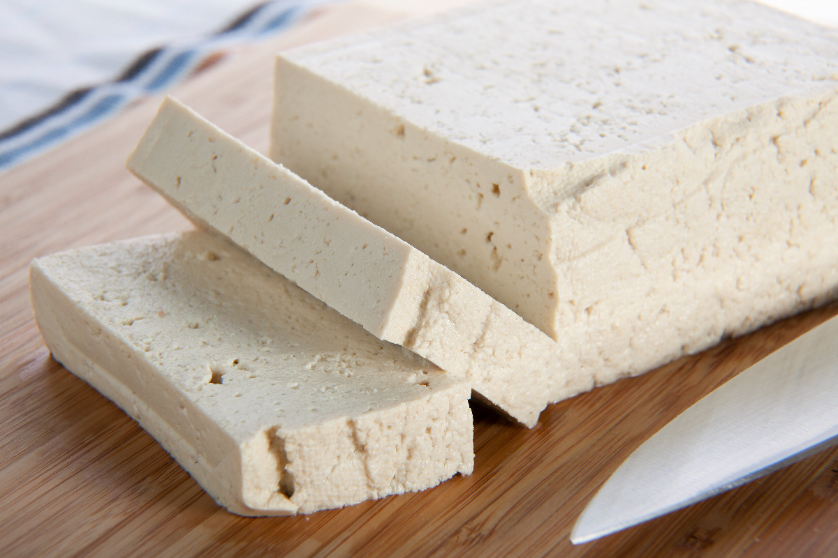 A block of protein rich tofu on a cutting board. 