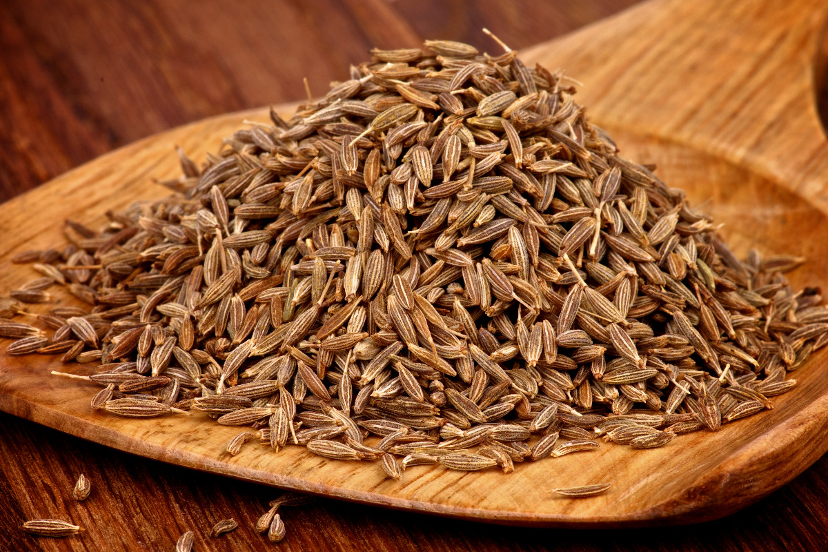 A wooden serving spoon full of cumin.